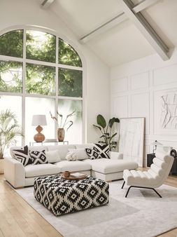 DFS Calix right hand facing large chaise end sofa in ivory boucle, Calix pattern large square footstool, and Calix ripple accent chair in ivory boucle.